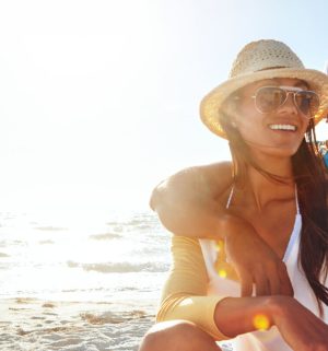 Young couple wearing hats, smiling and sitting on the beach