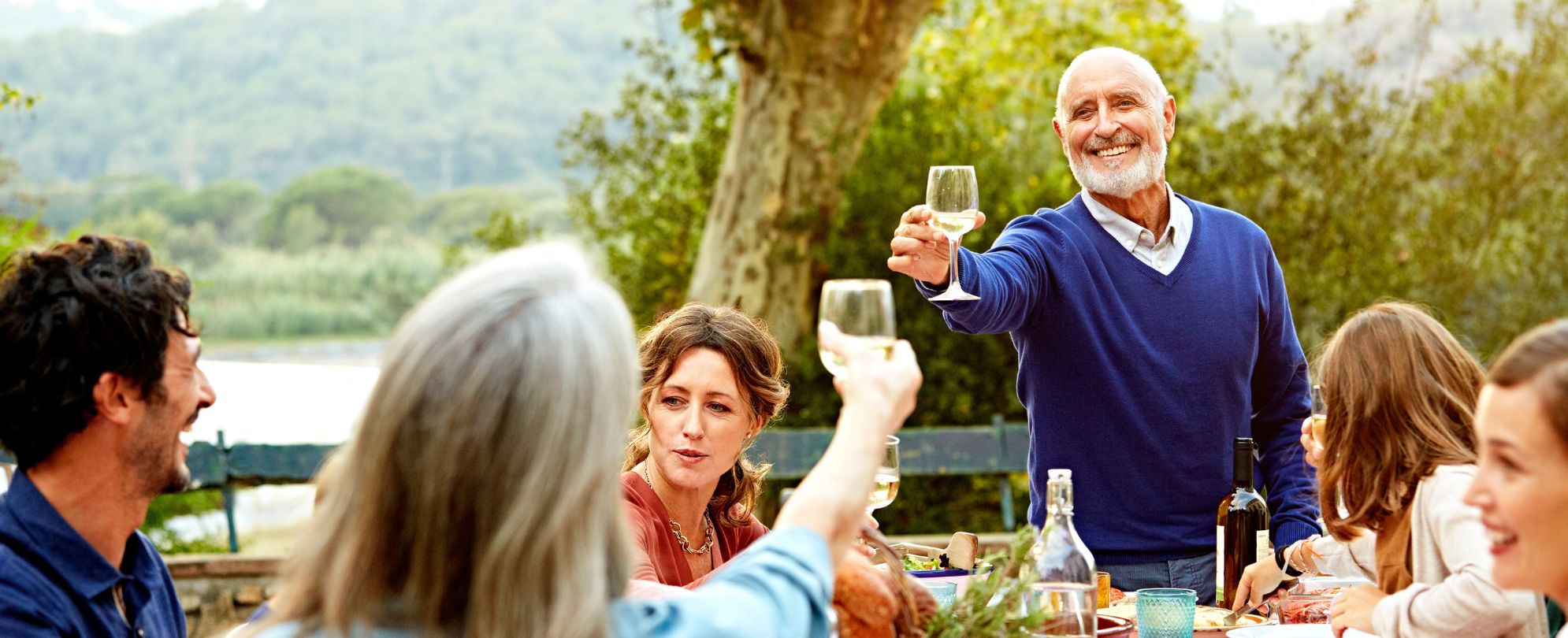 Mature man toasting his family at an outdoor meal