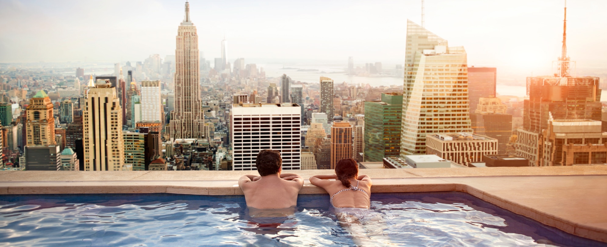 Couple leaning on the edge of an infinity pool overlooking city views 