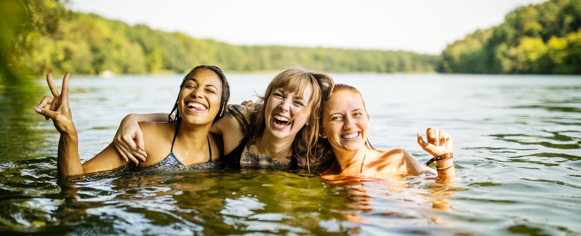A group of three girlfriends taking a fun photo together in the lake 