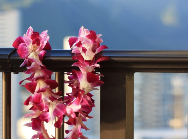 Purple orchid lei hanging on balcony railing 