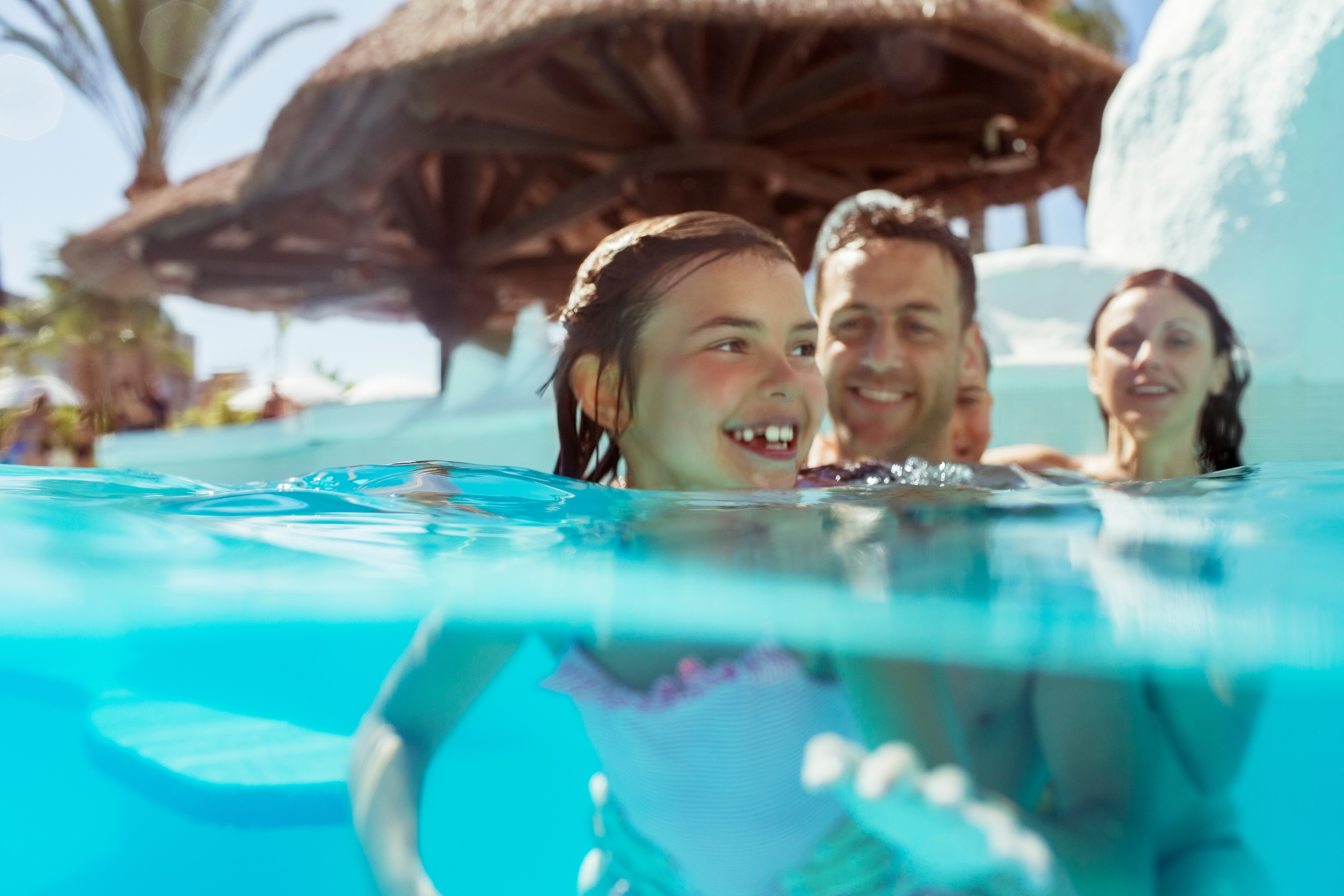 Family of four, smiling in pool