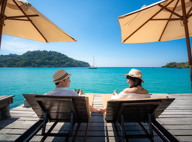 A man and a woman relaxing in a cabana facing the ocean. 