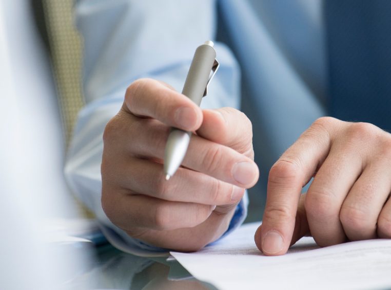 Close up of a timeshare attorneys hand, holding a pen, and reviewing an important timeshare document 