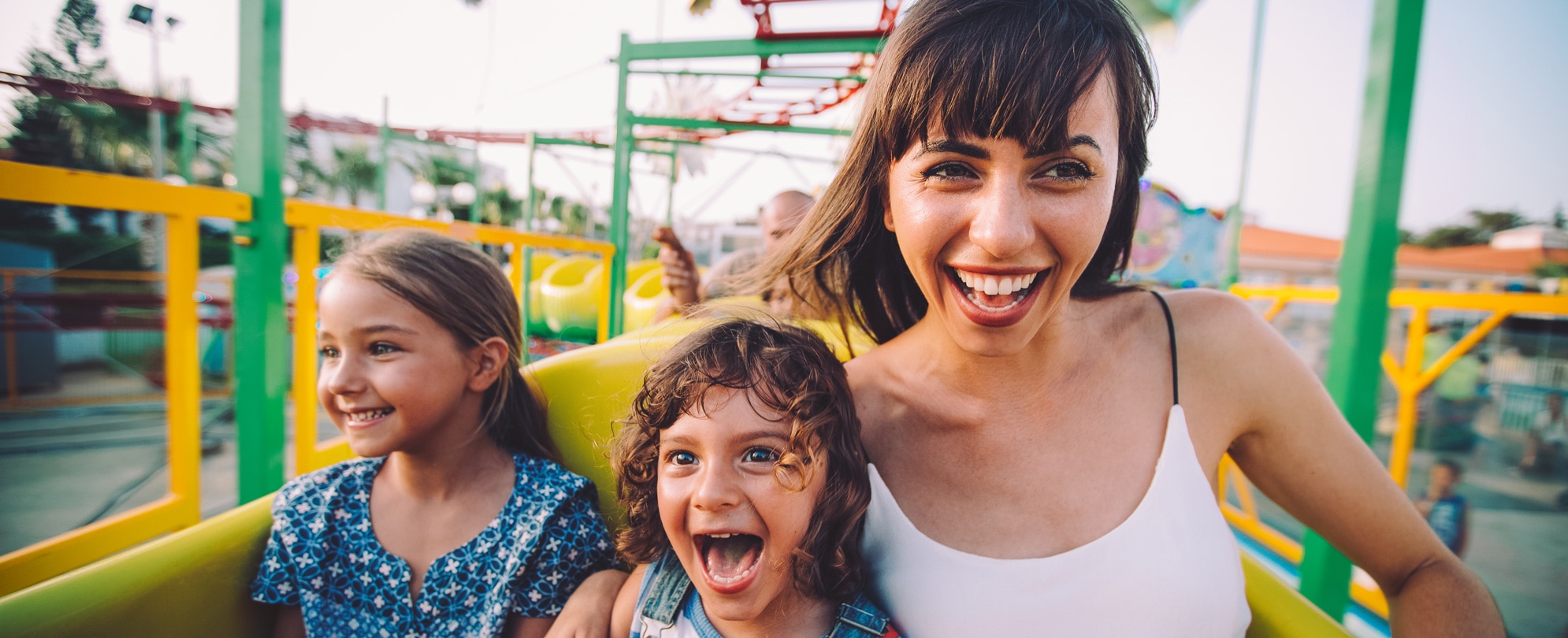Mother and two daughters laughing on a caterpillar amusement park ride 